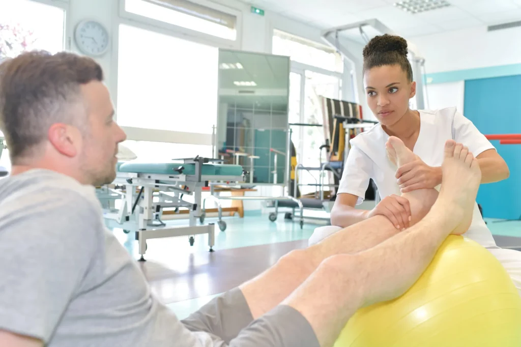 physiotherapist-moving-man-foot-resting formation TMS secteur sanitaire et médico-social